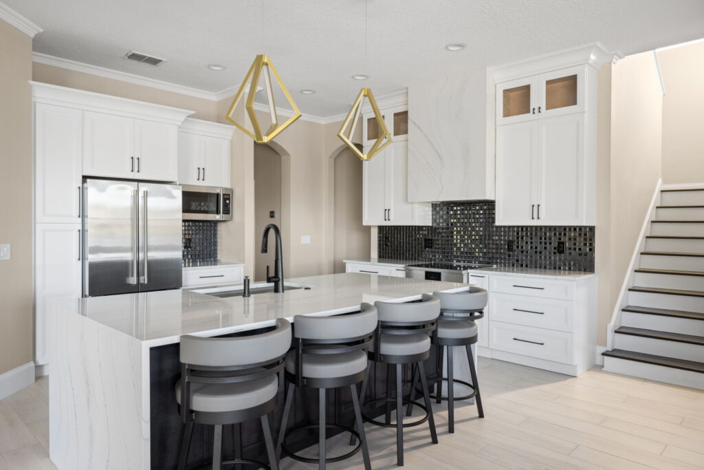 Modern white kitchen interior with geometric gold light fixtures and subtle tile accents