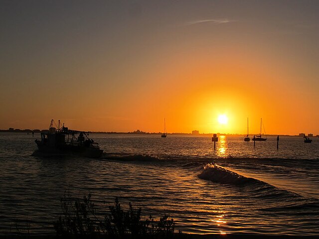 Boat sailing at sunset over calm waters.