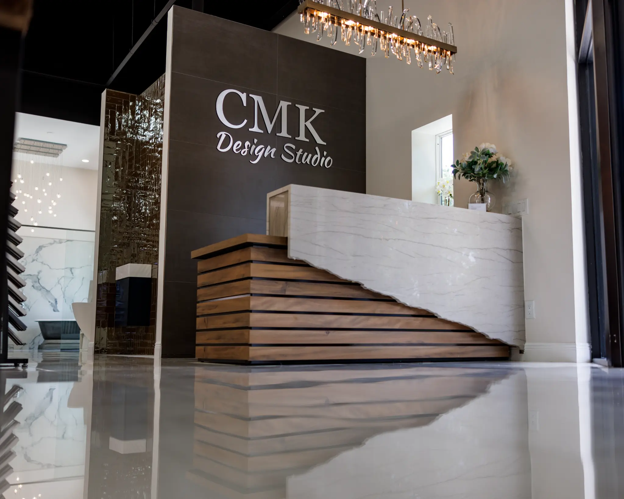 CMK Design Studio showroom entrance with marble reception desk, crystal chandelier, and polished floors in Tampa Florida