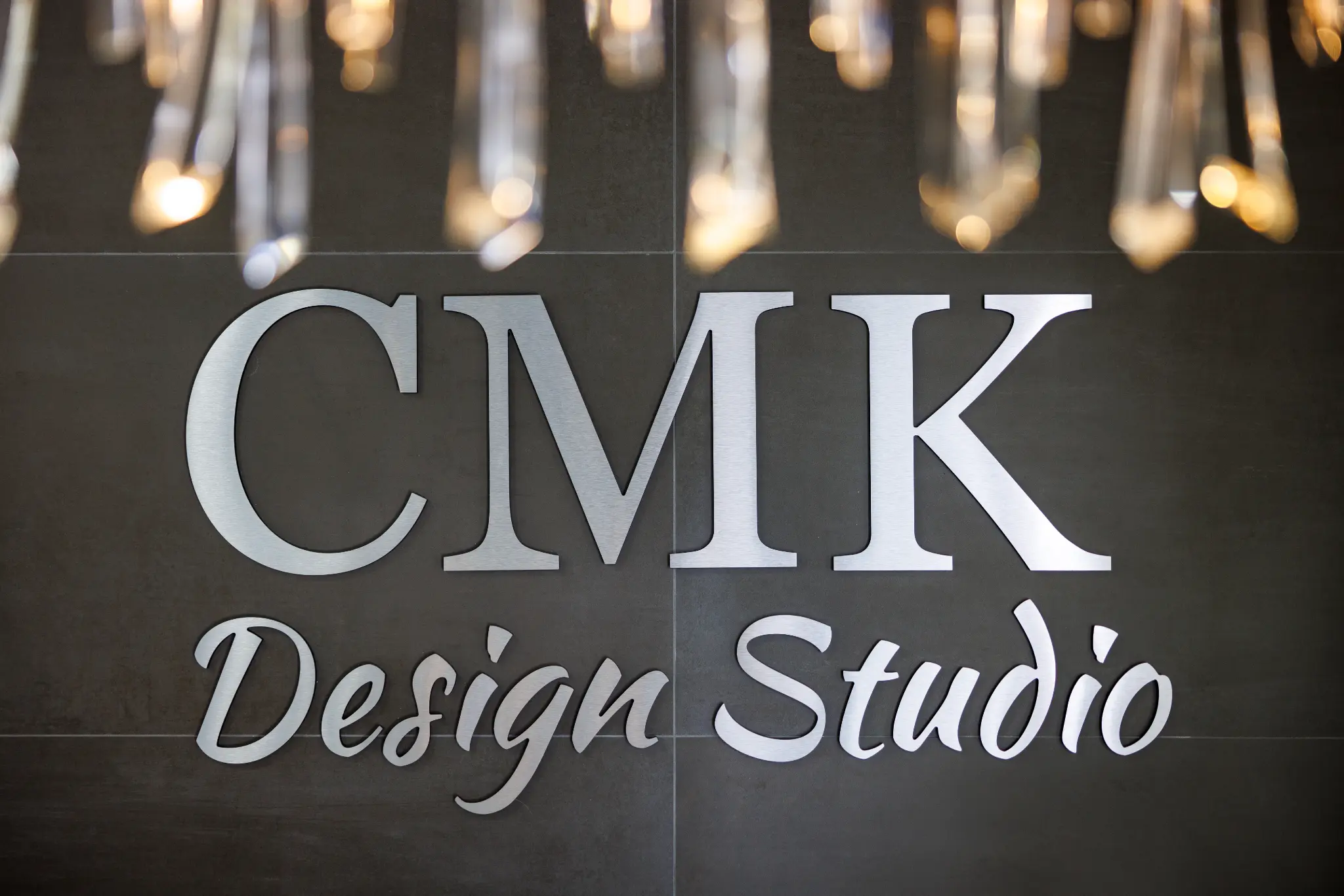 CMK Design Studio design showroom entrance with brushed metal signage and crystal chandelier in Tampa Florida